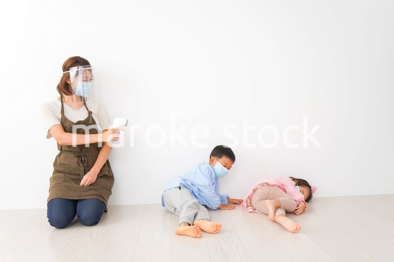 体温測定をする先生と幼稚園児