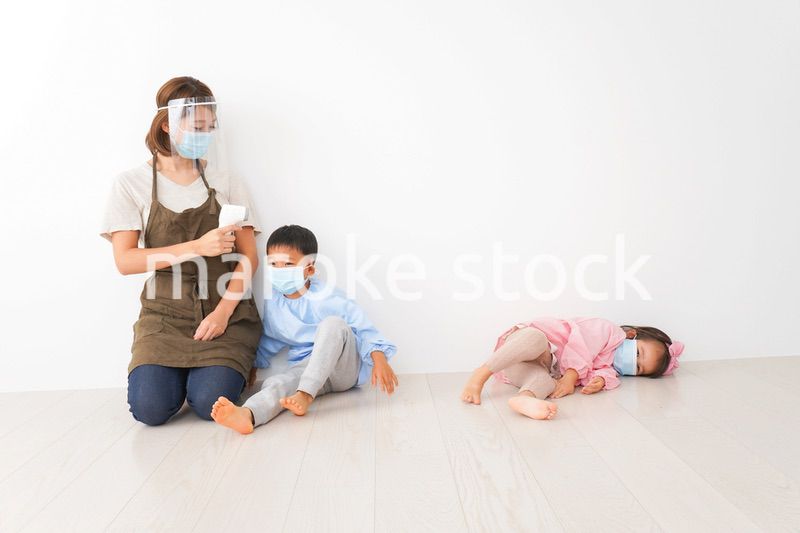 体温測定をする先生と幼稚園児