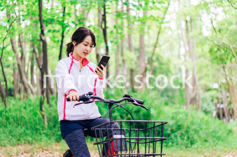 自転車に乗りながらスマホを使う女性