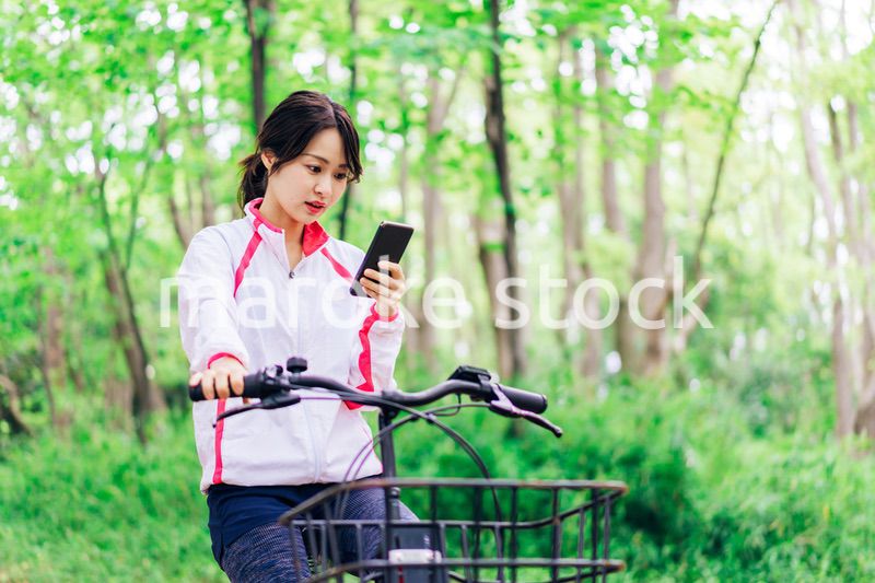 自転車に乗りながらスマホを使う女性