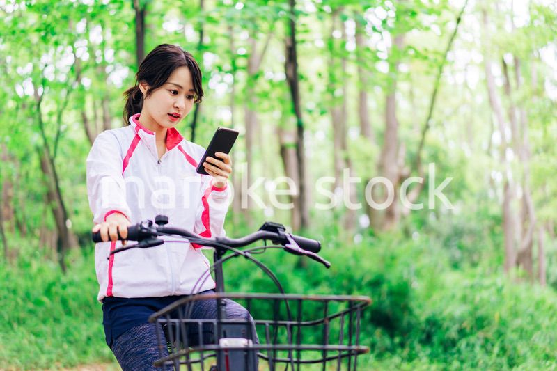 自転車に乗りながらスマホを使う女性