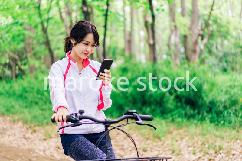 自転車に乗りながらスマホを使う女性