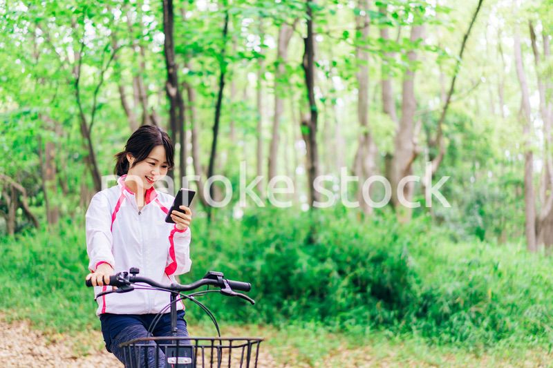 自転車に乗りながらスマホを使う女性