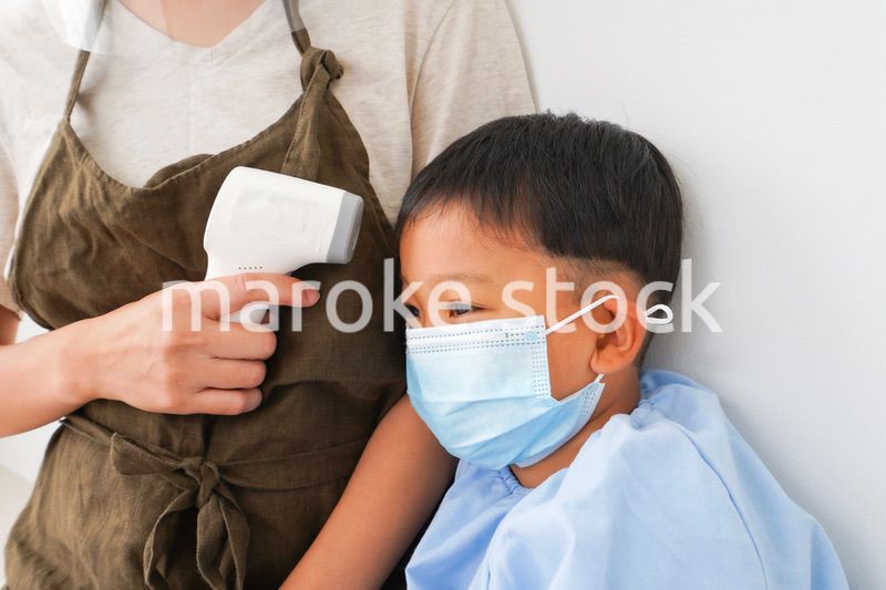 幼児の体温測定をする保育士