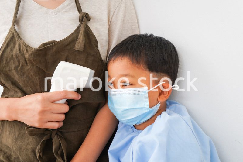 幼児の体温測定をする保育士