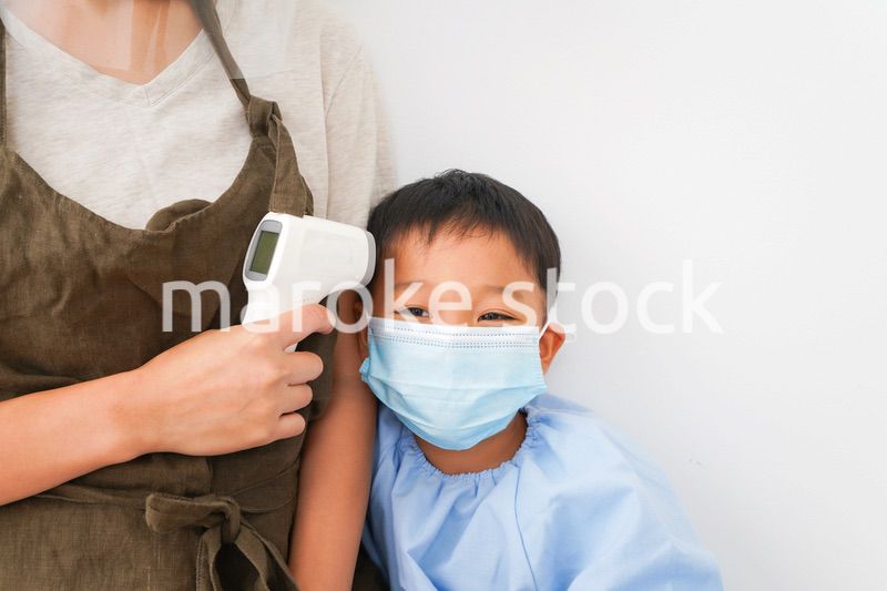 幼児の体温測定をする保育士