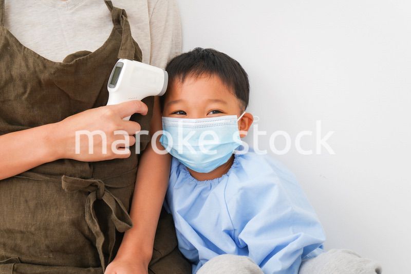 幼児の体温測定をする保育士