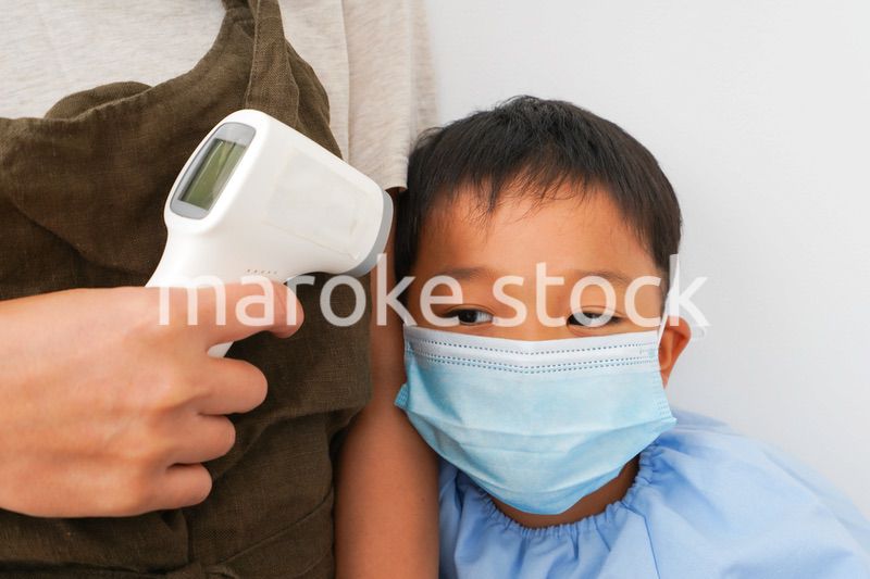 幼児の体温測定をする保育士