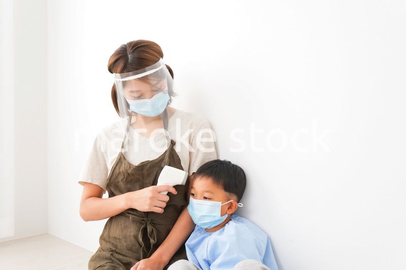 幼児の体温測定をする保育士