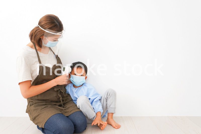 幼児の体温測定をする保育士