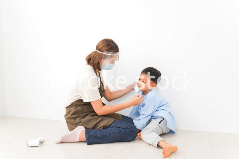 園児にマスクをつける保育士