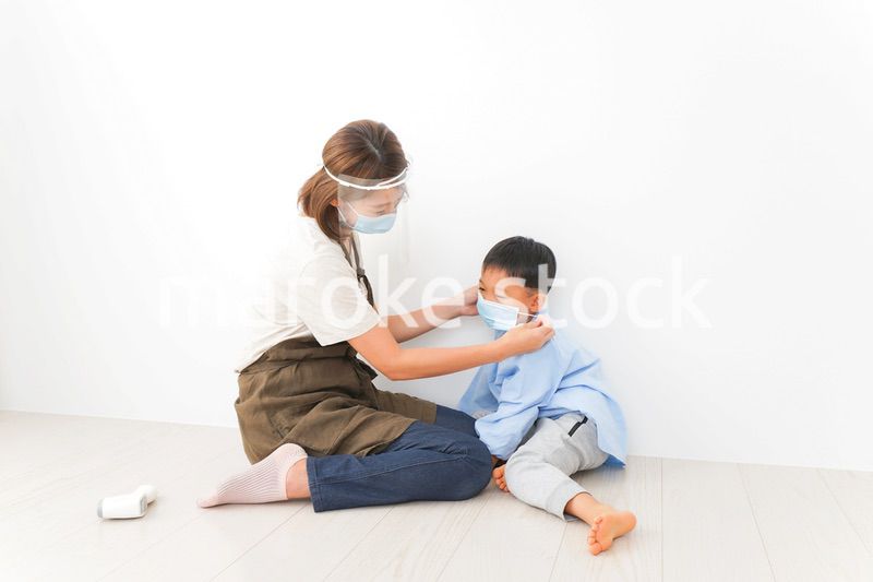 園児にマスクをつける保育士