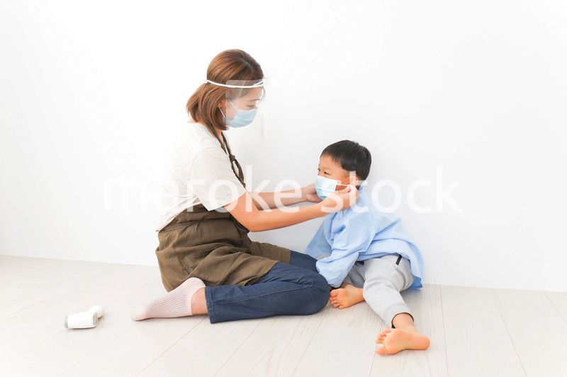 園児にマスクをつける保育士