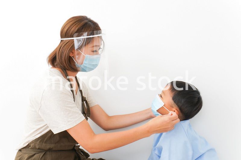 園児にマスクをつける保育士