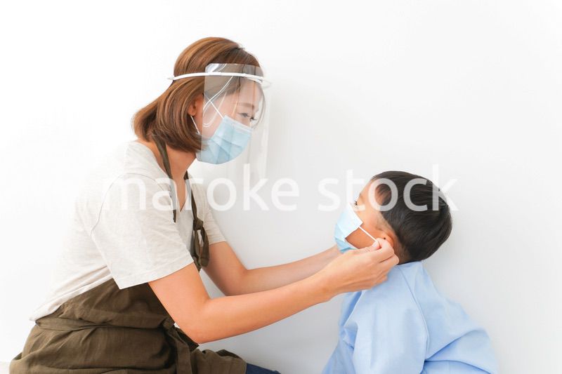 園児にマスクをつける保育士