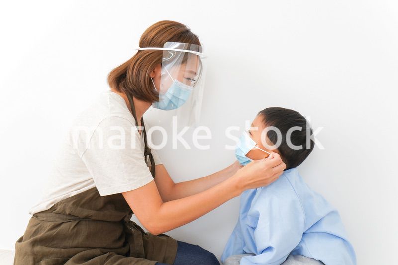 園児にマスクをつける保育士