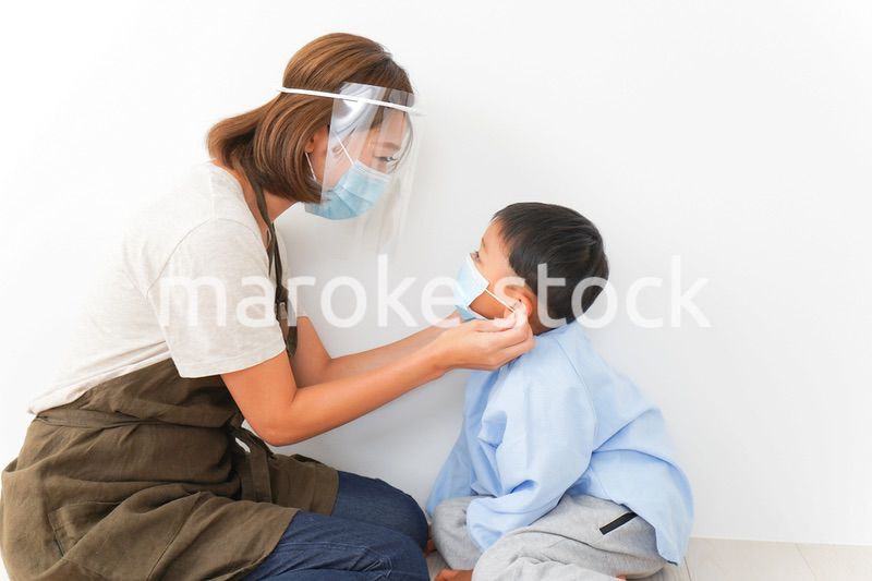 園児にマスクをつける保育士