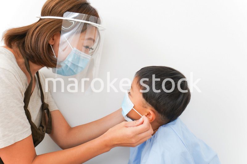 園児にマスクをつける保育士