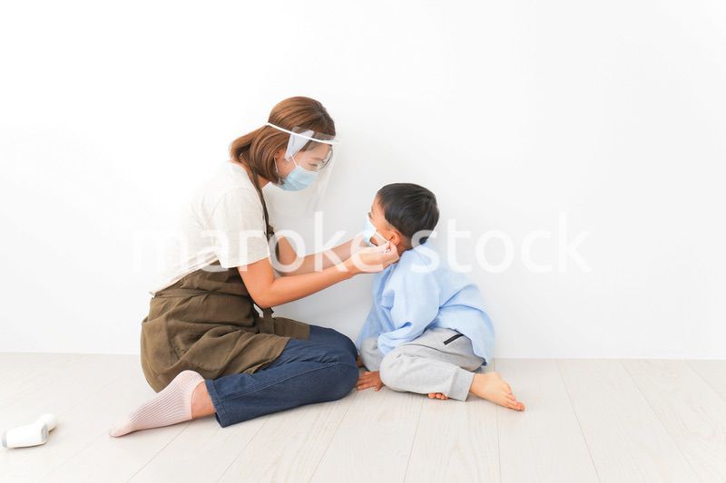 園児にマスクをつける保育士