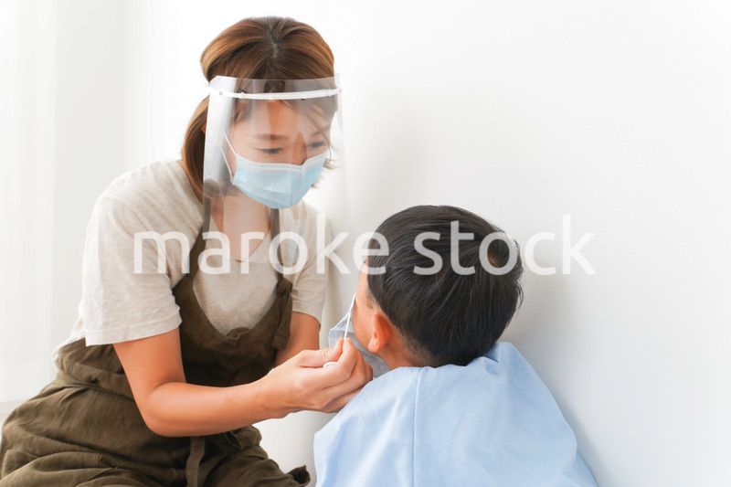 園児にマスクをつける保育士