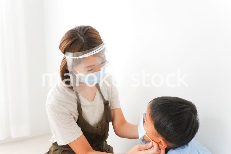 園児にマスクをつける保育士