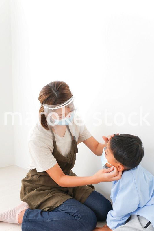 園児にマスクをつける保育士