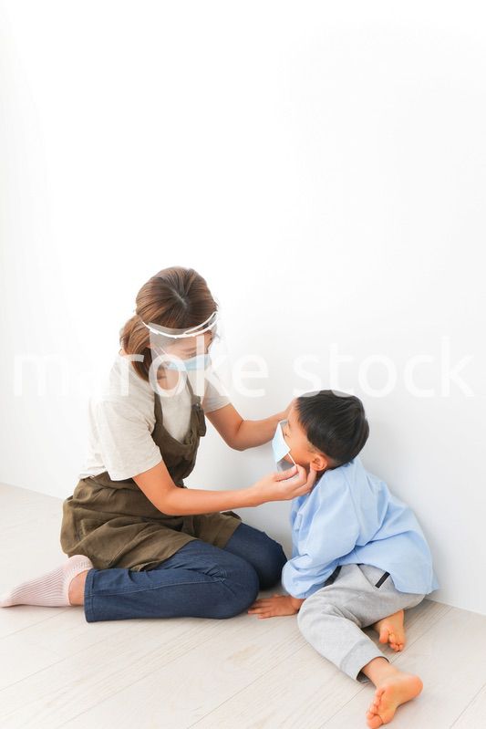 園児にマスクをつける保育士