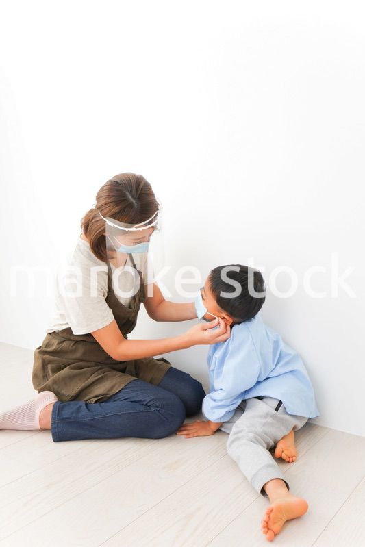 園児にマスクをつける保育士