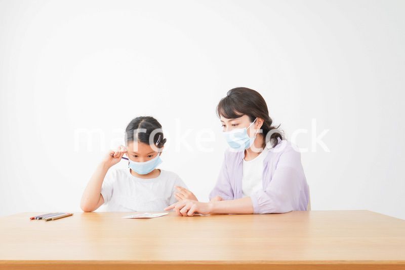 マスクをして小学生に個別指導をする先生