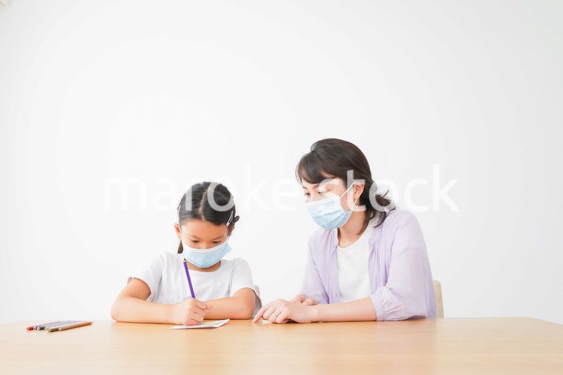 マスクをして小学生に個別指導をする先生