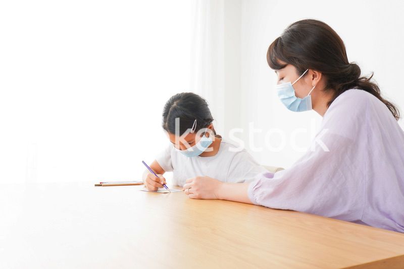 マスクをして小学生に個別指導をする先生