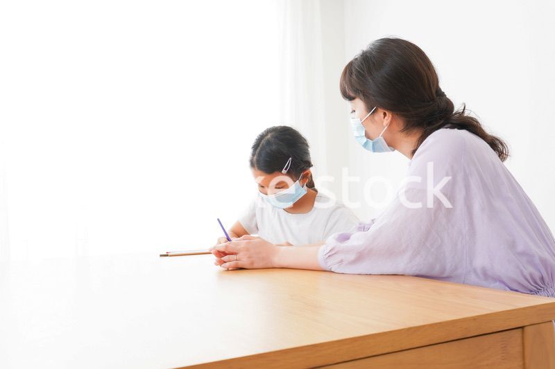 マスクをして小学生に個別指導をする先生