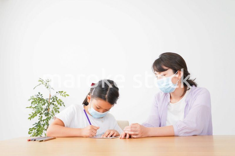 マスクをして小学生に個別指導をする先生