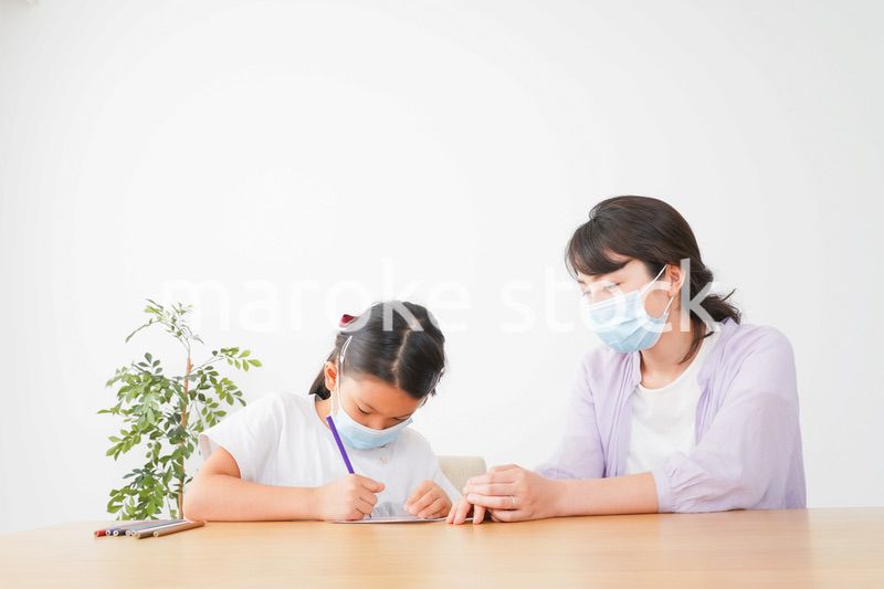 マスクをして小学生に個別指導をする先生