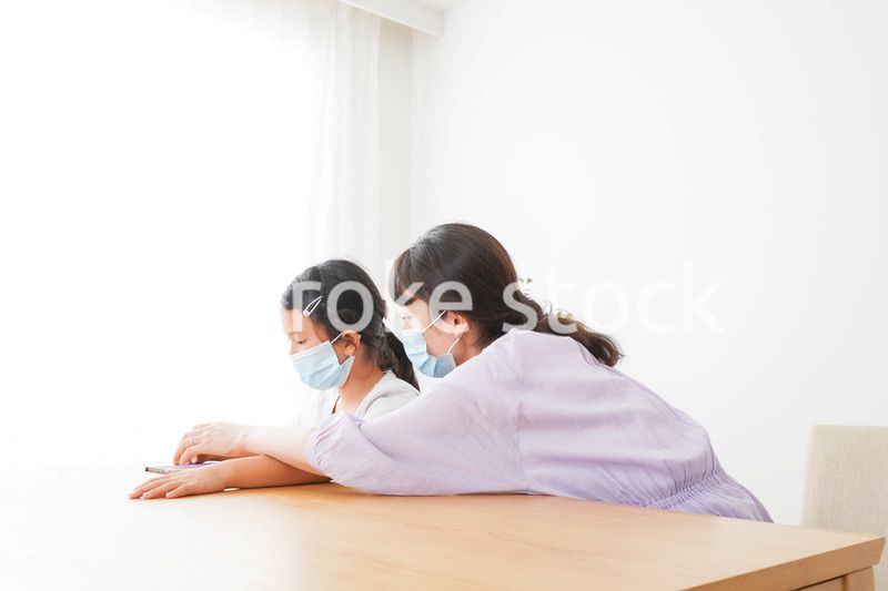 マスクをして小学生に個別指導をする先生