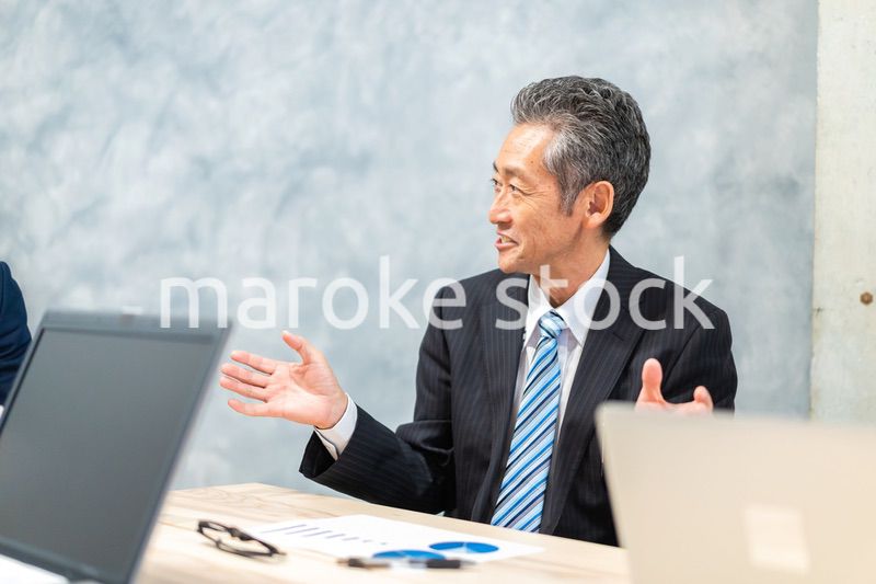 スーツで意見を述べる経営者