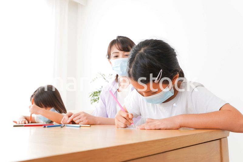 マスクを付けて勉強をする子供と塾講師