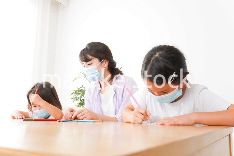 マスクを付けて勉強をする子供と塾講師
