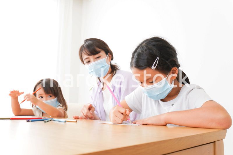 マスクを付けて勉強をする子供と塾講師