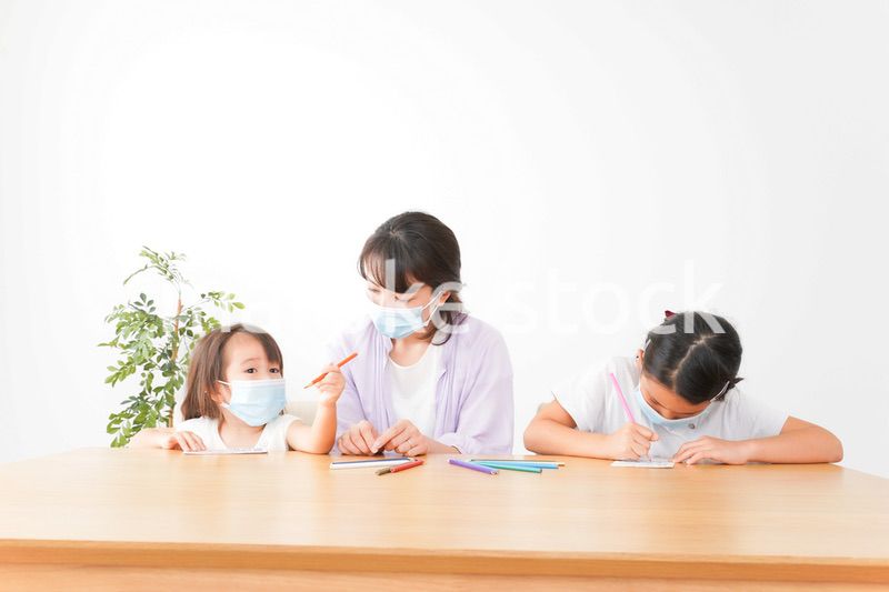 マスクを付けて勉強をする子供と塾講師