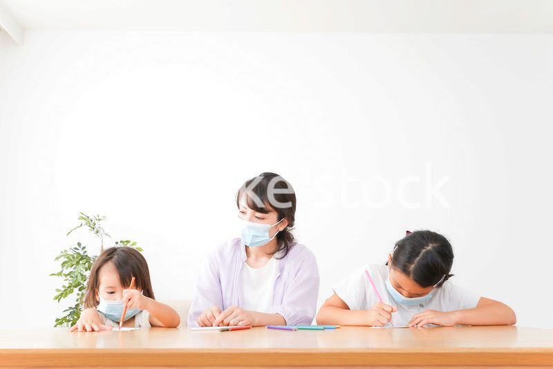 マスクを付けて勉強をする子供と塾講師