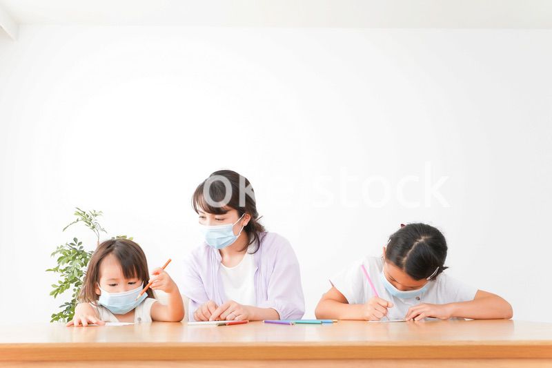 マスクを付けて勉強をする子供と塾講師