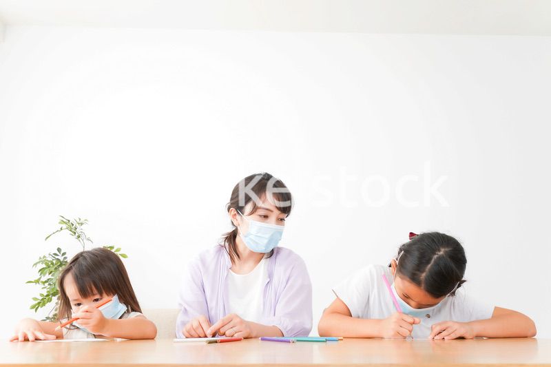 マスクを付けて勉強をする子供と塾講師