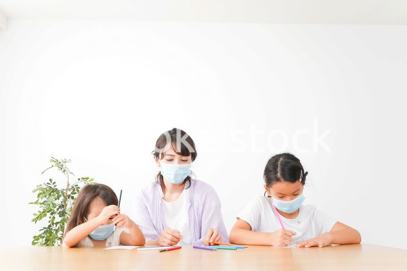 マスクを付けて勉強をする子供と塾講師