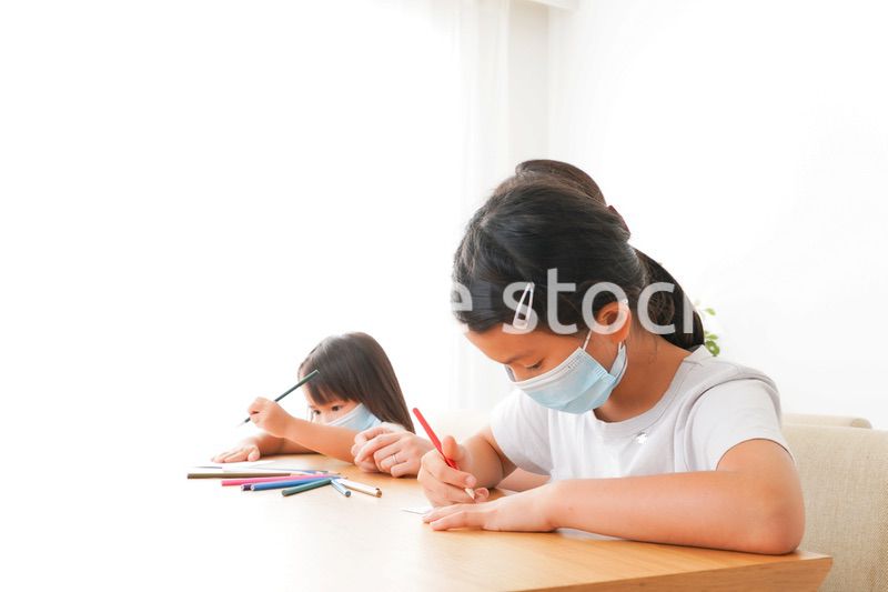 マスクを付けて勉強をする子供と塾講師
