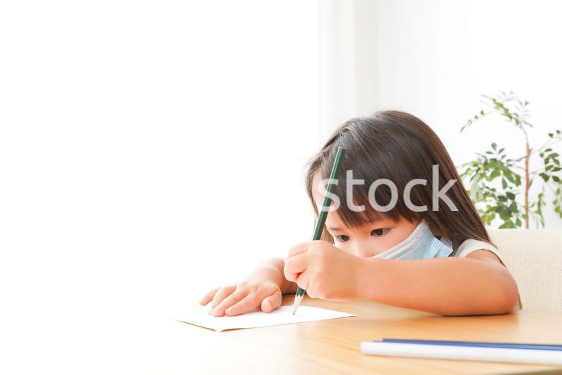 マスクを付けて勉強をする子供と塾講師