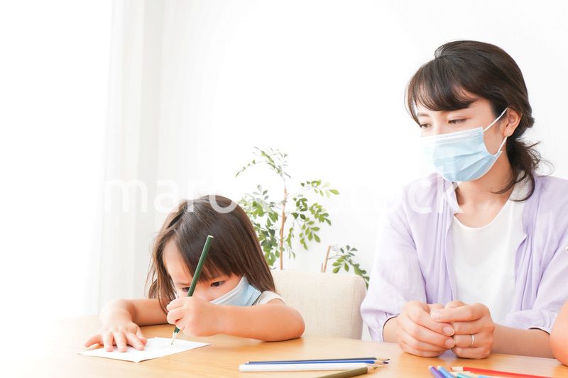 マスクを付けて勉強をする子供と塾講師