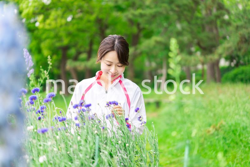 庭で花の世話をする若い女性