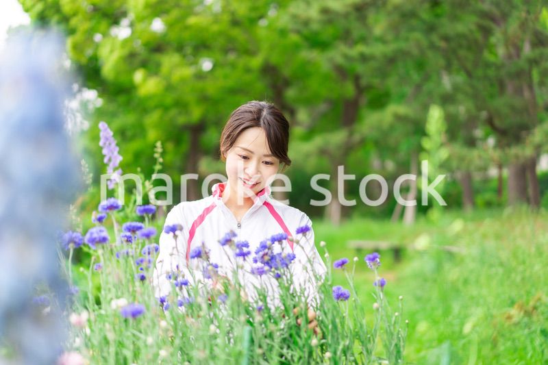 庭で花の世話をする若い女性