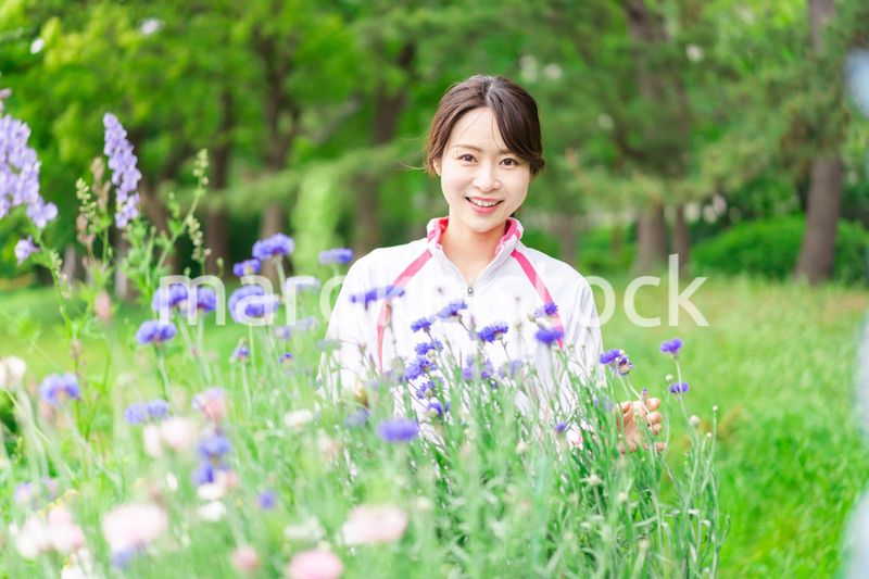 庭で花の世話をする若い女性